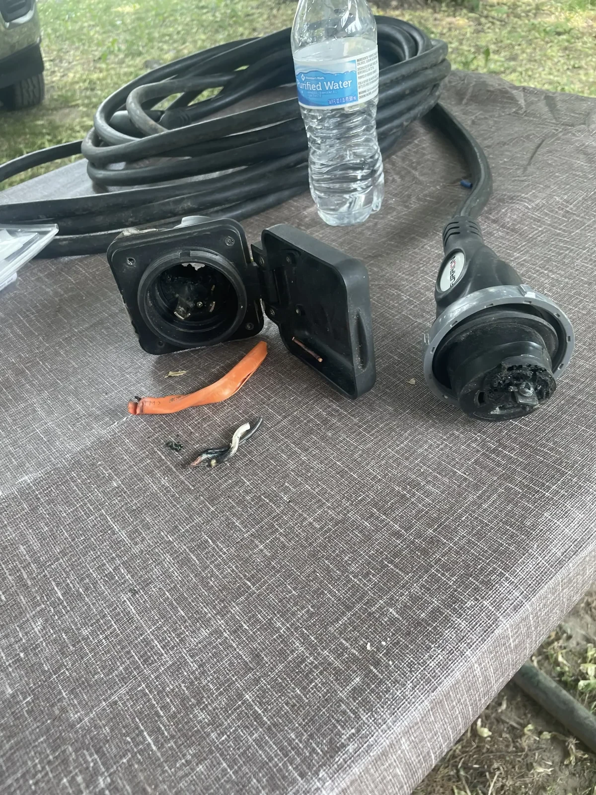 A burned and melted RV shore power inlet and cable — the failure mode Strain Guard prevents